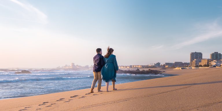 Casal de mãos dadas a caminhar pela praia