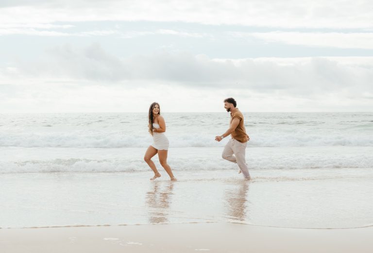 Casal a correr pela praia a sorrir