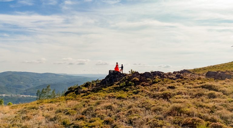 Casal de mãos dadas numa colina com vista
