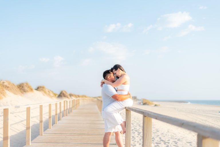 Casal abraçado a sorrir no passadiço da praia