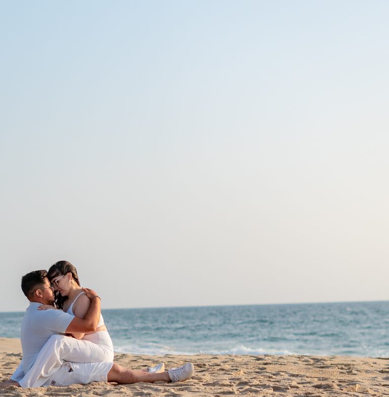 Casal sentado na areia na praia abraçado