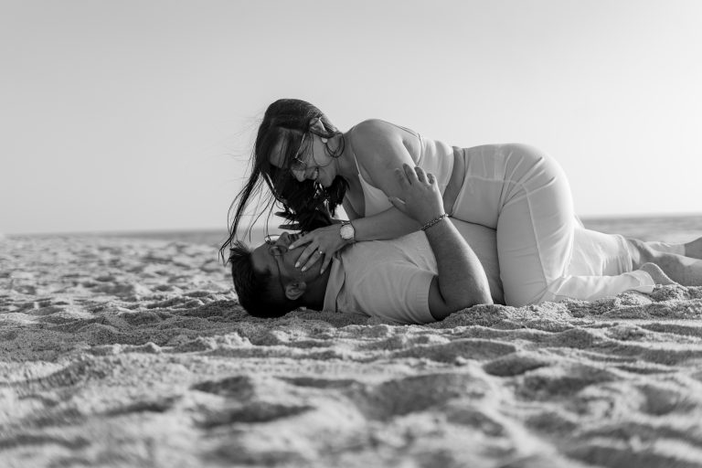 Casal deitado na areia na praia abraçado