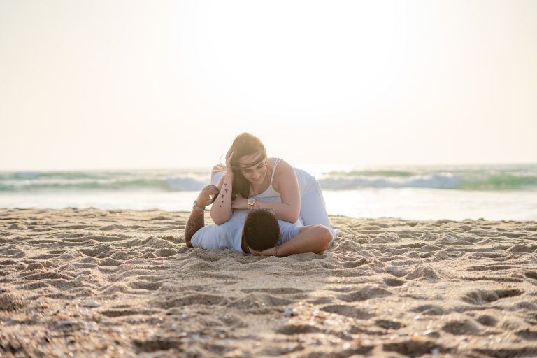 Casal deitado na areia na praia abraçado