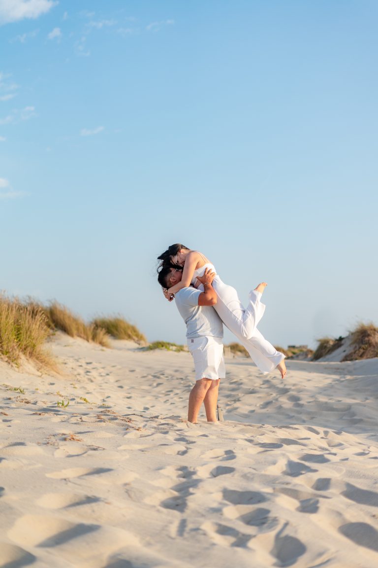 Casal abraçado na praia a sorrir