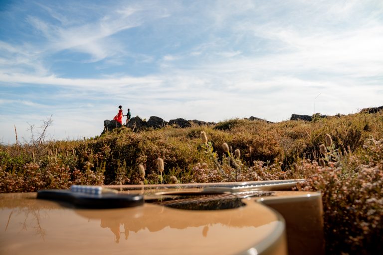 Casal abraçado num campo com viola como foreground