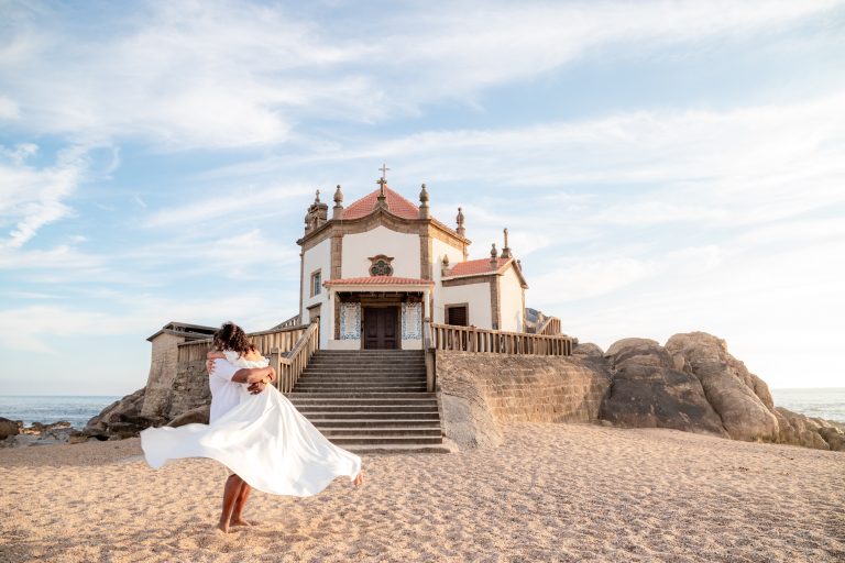 Casal feliz abraçado numa praia em frente à igreja